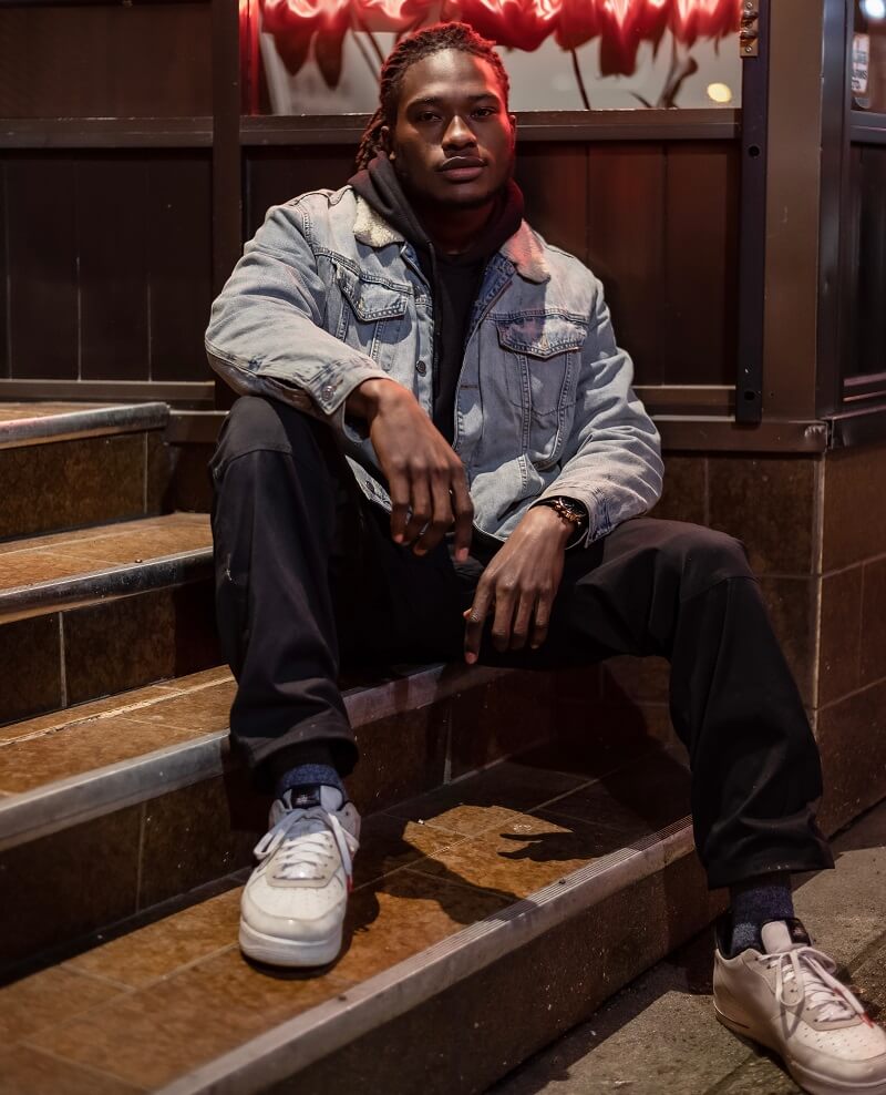 one man wearing a blue jean jacket and white sneakers.